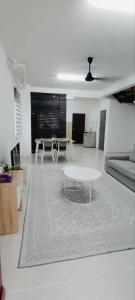 a white living room with a table and a couch at HomestayFA in Gua Sai +4 photos