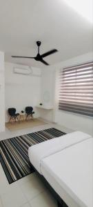 a room with a bed and two chairs and a ceiling fan at HomestayFA in Gua Sai