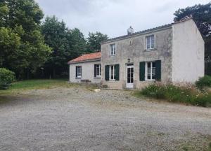 ein altes Steinhaus mit grünen Rollläden auf einem Feld in der Unterkunft Gîte du Tilleul - un petit coin de nature in Vallet + 11 Fotos