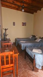 a room with three beds and a table and a table and chairs at Hosteria LA VIEJA CARRETA in Purmamarca