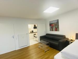 a living room with a black couch and a kitchen at Anacoco Suites in Würselen