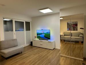 a living room with a tv and a chair at Anacoco Suites in Würselen