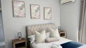 a bedroom with a bed with four pictures on the wall at Gemmel Place Villa in Durban +29 photos