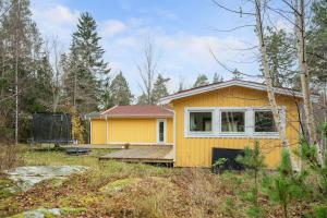 a yellow house in the middle of a forest at Modern family home next to Mälaren in Mariefred in Mariefred