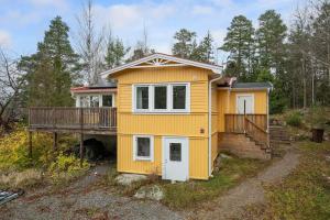 a yellow house with a porch and a deck at Modern family home next to Mälaren in Mariefred in Mariefred