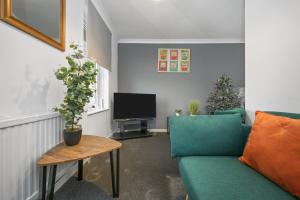 ein Wohnzimmer mit einem grünen Sofa und einem Fernseher in der Unterkunft The Randolph 2-Bed MK9 Flat Short- Long-Stay Family & Contractor Friendly Free Parking close to Theatre, Now with lounge in Milton Keynes
