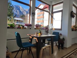 a table and chairs in a room with windows at Little Bear Busteni 3 in Buşteni