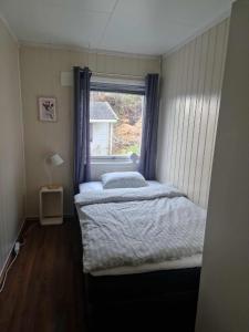 two beds in a small room with a window at House with terrace and a big garden in centrum of Lyngseidet in Lyngseidet +20 photos