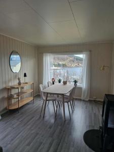 a dining room with a table and chairs and a large window at House with terrace and a big garden in centrum of Lyngseidet in Lyngseidet