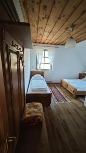 a bedroom with two beds and a wooden ceiling at Kolonics Pincészet Vendégház Somló in Somlóvásárhely