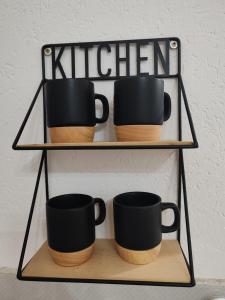 a shelf with four black coffee mugs on it at Isi beauty in Jagodina