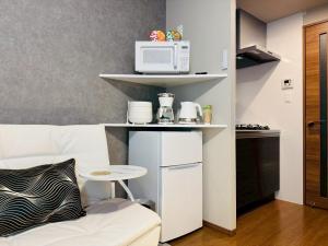 Eine Küche mit einer Couch und einer Mikrowelle auf einem Regal in der Unterkunft LuxurySweet 博多駅南52 in Fukuoka