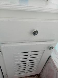 a white dresser with a metal knob on it at Nature Lodge Retreat in Portland in Port Antonio