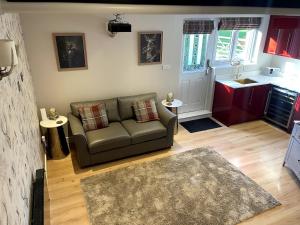 a living room with a couch and a kitchen at Greenfinch Lodge in Norton Heath