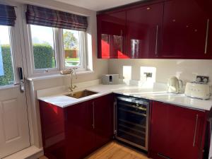 a kitchen with red cabinets and a sink at Greenfinch Lodge in Norton Heath