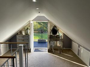 an attic hallway with a staircase leading to a door at Greenfinch Lodge in Norton Heath