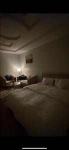 Un dormitorio con una gran cama blanca y un sofá. en غرفة بدورة مياة بدخول ذاتي, en Al Kharj