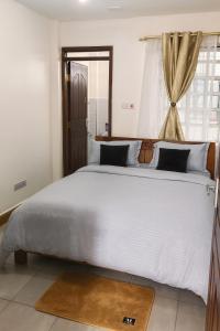Una cama blanca grande en una habitación con ventana. en Loresho Luxe stay, en Nairobi