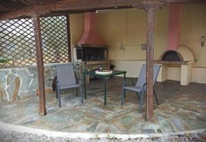 un patio avec une table, des chaises et une cheminée dans l'établissement Theonimfi Villa for 5 with pool and Sea View, à Loutra Elenis