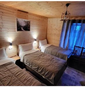 a room with two beds in a log cabin at Bujtina Pllumi Theth in Theth