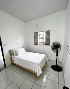 une chambre blanche avec un lit et un ventilateur dans l'établissement Apartamento mobiliado - Próximo ao Estádio Olímpico do Mangueirão, à Belém