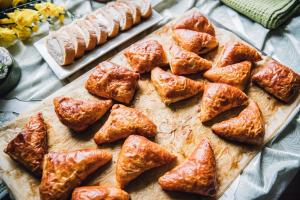 a wooden cutting board with bread and pastries on it at Villa River Rose in Jõesuu