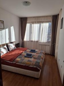 a bedroom with a bed and a large window at Апартаменты в Belvedere in Bansko