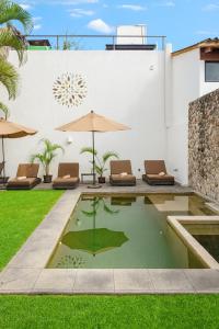 a pool in the backyard of a house with chairs and an umbrella at Mocca Hotels in Tepoztlán