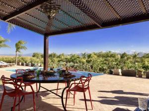 Un patio con mesa y sillas y una piscina. en Villa Dar Waw Marrakech, en Tameslouht
