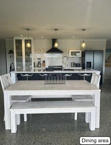 eine Küche mit einem weißen Tisch und zwei weißen Bänken in der Unterkunft Peaceful retreat in big sky country, near beach in Mangawhai