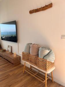 a room with a wicker bench with a tv on a wall at הדירה- C Lake, סי כנרת in Migdal