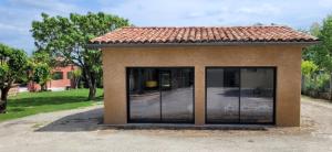 een klein huis met glazen deuren in een tuin bij Gîte de la Côte Rouge in Saint-Nauphary
