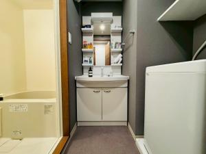 ein kleines Badezimmer mit Waschbecken und Kühlschrank in der Unterkunft LuxurySweet 博多駅南53 in Fukuoka + 11 Fotos