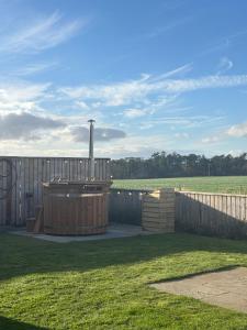 a hot tub in a yard next to a fence at Border View Cottage in Duddo