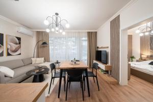 ein Wohnzimmer mit einer Couch und einem Tisch und Stühlen in der Unterkunft Бизнес & Арт апартамент - до Панаира и Капана in Plowdiw