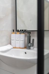 ein Badezimmer mit einem Waschbecken, auf dem drei Flaschen stehen in der Unterkunft Бизнес & Арт апартамент - до Панаира и Капана in Plowdiw + 29 Fotos