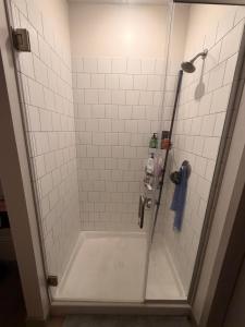 a shower in a bathroom with white tiles at Modern Midtown Retreat Luxury Car Option in Kansas City