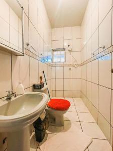 a bathroom with a sink and a toilet with a red seat at Pousada da Ana in Estivado