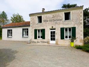 ein weißes Gebäude mit grünen Fensterläden und einem Gebäude in der Unterkunft Gîte du Cerisier - Studio nature détente in Vallet