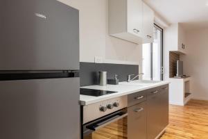 a white kitchen with a stove and a sink at L'Odile - 2 pers hypercenter in Bourg-en-Bresse