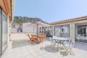 a patio with a table and chairs and an umbrella at Gîtes Pierre Pelou Tautavel in Tautavel