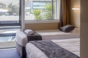 two beds in a room with a window at Recreation Hotel in Greymouth