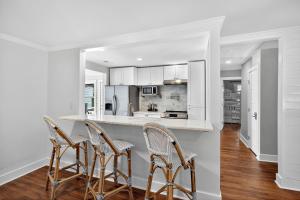 eine Küche mit weißen Schränken und Barhockern in der Unterkunft AV4-22: 4 22nd Avenue in Isle of Palms