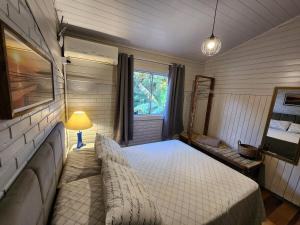 a bedroom with a bed and a couch and a window at Casa de praia com piscina e jacuzzi totalmente privativa in Imbituba +49 photos