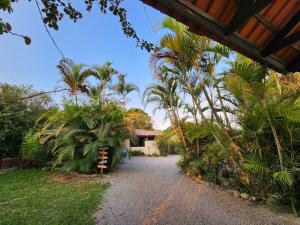 a driveway leading to a house with palm trees at Casa de praia com piscina e jacuzzi totalmente privativa in Imbituba