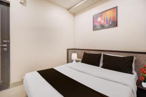 アーメダバードにあるHotel O Vatva Railway Station Formerly Anmol Palaceのベッドルーム(白い大型ベッド、黒い枕付)