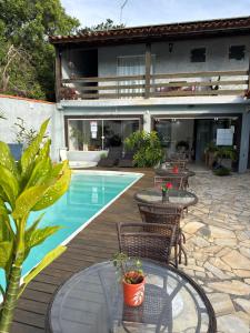 a patio with tables and chairs next to a pool at Pousada Sereia de Geriba in Búzios
