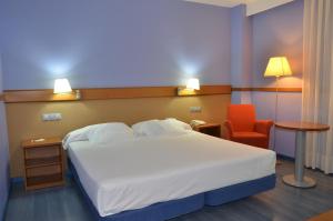 a bedroom with a large white bed and a chair at Hotel Murrieta in Logroño