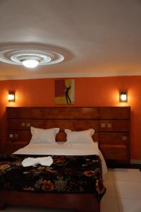 a bedroom with a large bed with an orange wall at HÔTEL Michou in Bafoussam