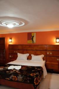 a bedroom with a large bed with an orange wall at HÔTEL Michou in Bafoussam +17 photos
